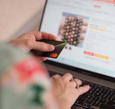 Engaging in online shopping using a credit card with a laptop for convenience and ease.